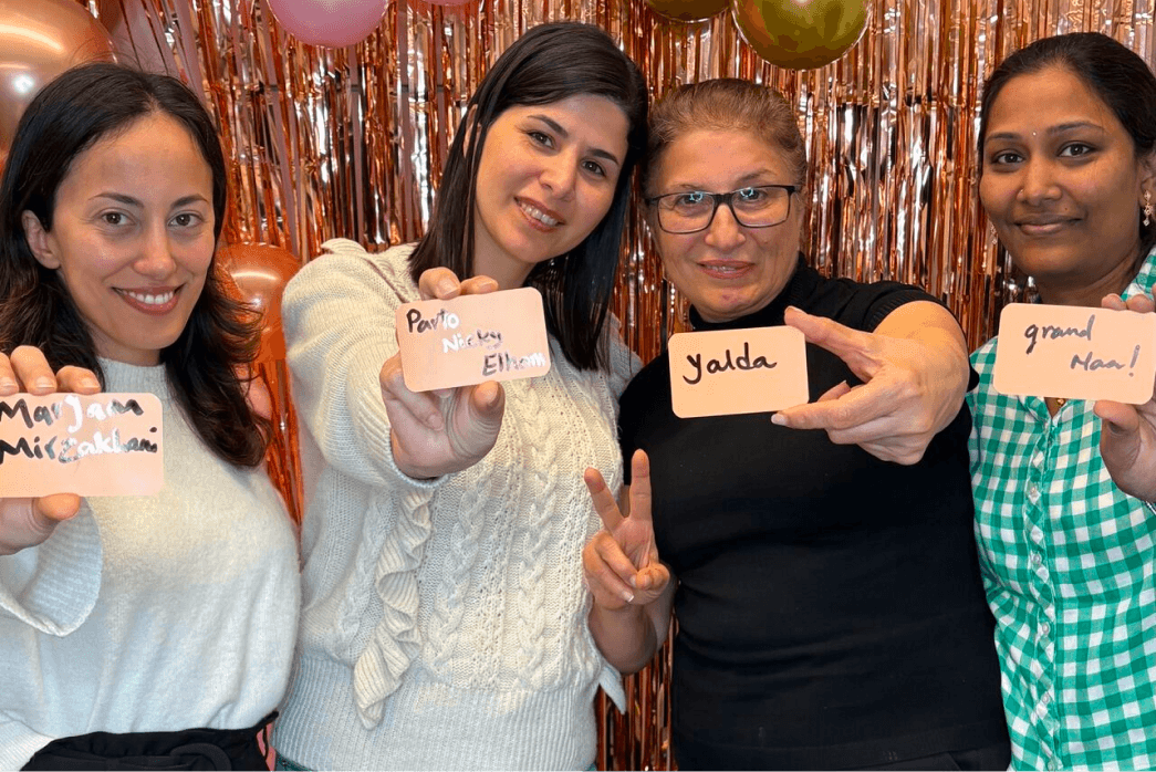Group of Fintel Connect Employees in front of a backgrounds with tinsel-like streamers holding up cards to the camera