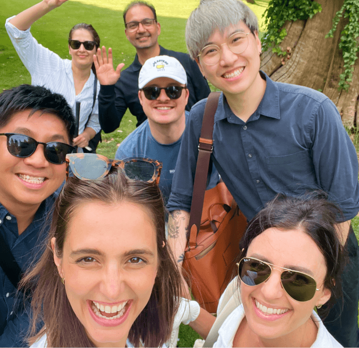 A group of Fintel Connect employees looking at the camera against a grassy field and a tree